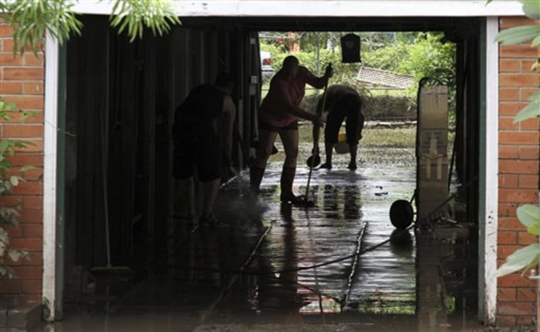 Local residents clear away the mud from their flooded home in Brisbane, Australia, Friday, Jan. 14, 2011. Parts of Brisbane reopened as deadly floodwaters that had swamped entire neighborhoods recede, revealing streets and thousands of homes covered in a thick layer of putrid sludge. (AP Photo/Tertius Pickard)